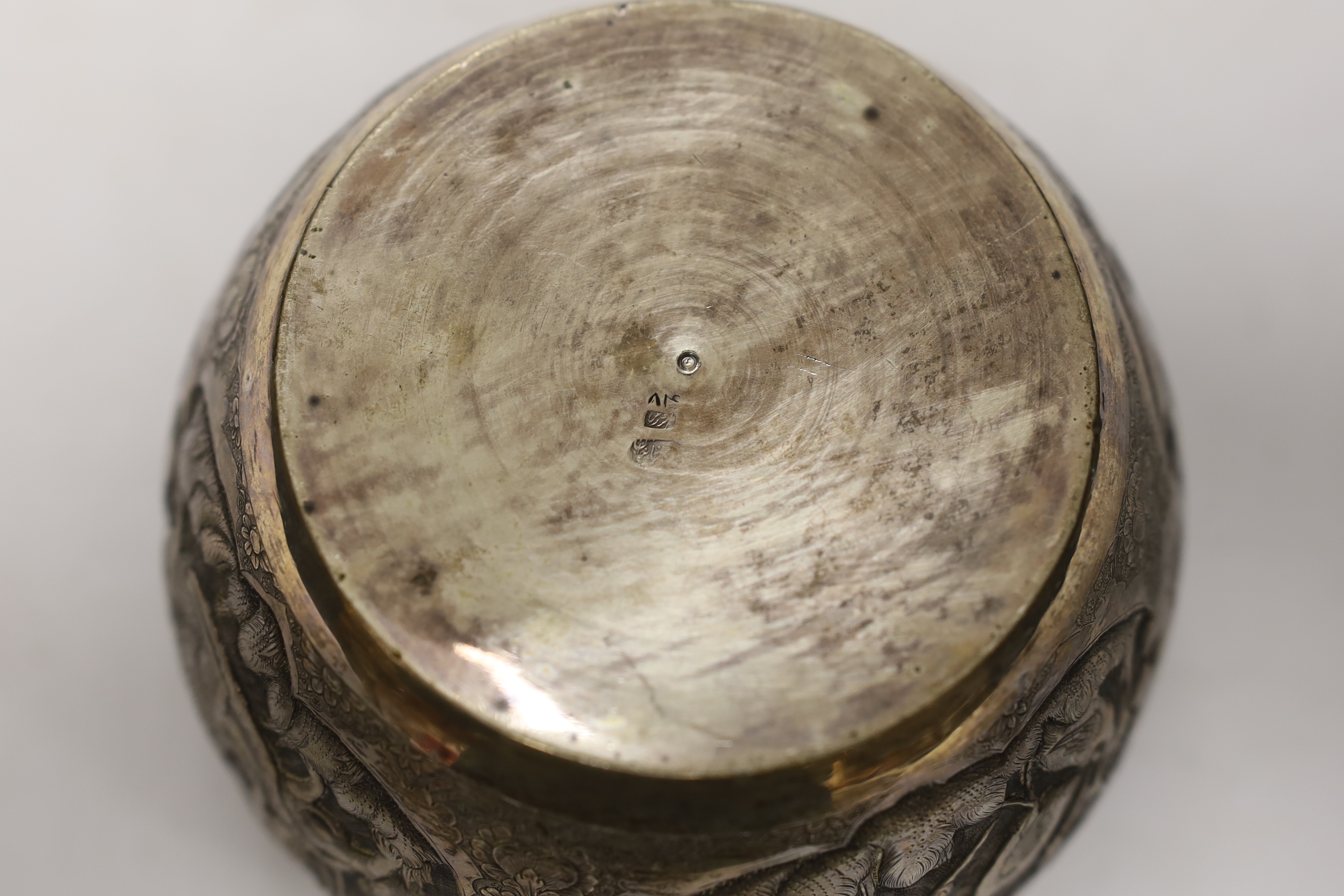 A Persian white metal bowl decorated in relief with animals and flowers, indistinct marks to the base, 16cm wide